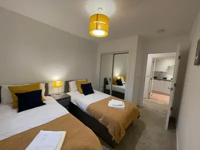 a bedroom with two beds and a room with a window at 2 bedroom luxury flat in quiet village of Bishopton in Bishopton