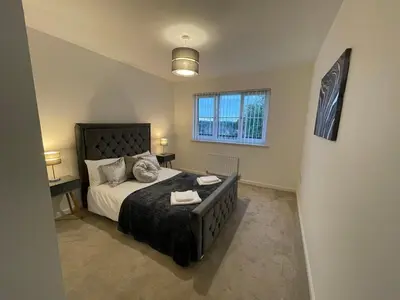 a bedroom with a large bed and a window at 2 bedroom luxury flat in quiet village of Bishopton in Bishopton