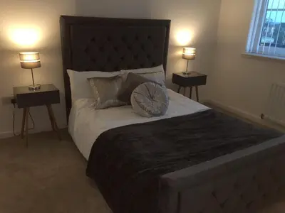 a bedroom with a large bed with two lamps at 2 bedroom luxury flat in quiet village of Bishopton in Bishopton