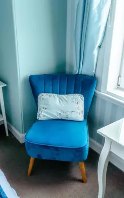 a blue chair with a pillow on top of it at Dawn Break Guest House in Largs