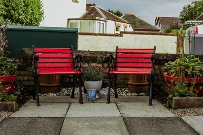 two red benches sitting in front of a fence at Dawn Break Guest House in Largs