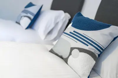 a bed with blue and white pillows on it at Cross Road Apartment in Paisley