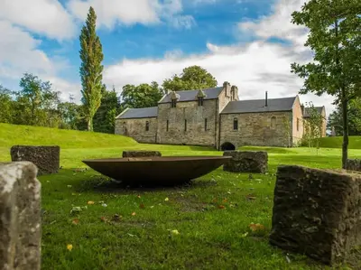 an old stone building with a boat in the grass at Stunning Edinburgh 1820s stables converted house in Ratho