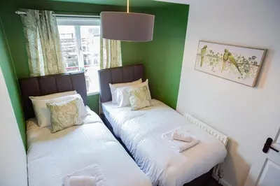 two beds in a room with green walls at The Marine - Balcony - Beach View - Coorie Doon Stays in Ayr
