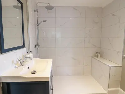 a white bathroom with a shower and a sink at Feus Holiday Cottage in Auchterarder