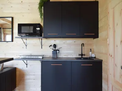 a kitchen with black cabinets and a sink at Pinewood Cabin in Saline