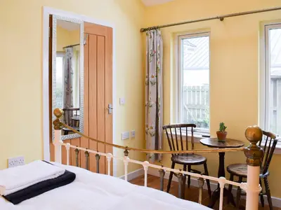 a bedroom with a bed and a table and chairs at Puddingstone Cottage in Gartmore