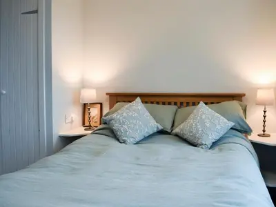 a blue bed with two pillows and two tables at Puddingstone Cottage in Gartmore