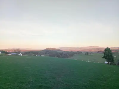 a field of green grass with the hills in the background at Puddingstone Cottage in Gartmore