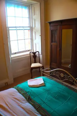 a bedroom with a bed and a chair and a window at Grand top floor apartment in the Royal Bank House in Maybole