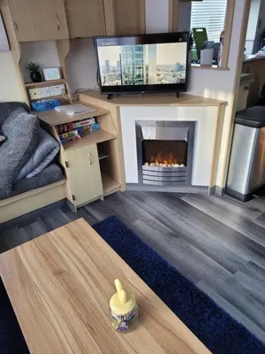a living room with a fireplace and a flat screen tv at The Rabbit Hill Holiday Home in Ballantrae