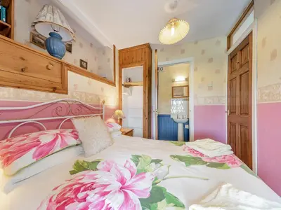 a bedroom with a large bed with pink flowers on it at The Bothy - Uk37414 in Bunessan