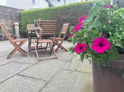 two chairs and a table and a plant with pink flowers at Allerton - Victorian Character Home in Stirling in Stirling