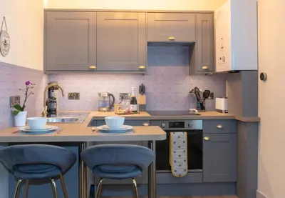 a kitchen with gray cabinets and blue bar stools at Station View, Dunblane in Dunblane