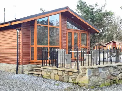 a wooden cabin with a fence in front of it at Willow Lodge Auchterarder in Auchterarder