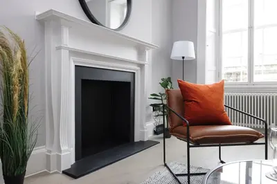 a living room with a chair and a fireplace at JOIVY Luxurious Apt on Notable George Street in Edinburgh