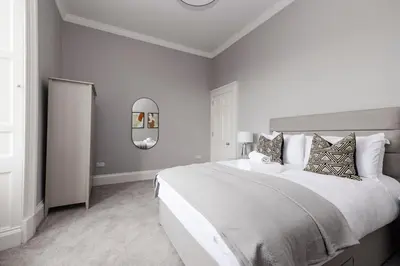 a white bedroom with a large bed with pillows at JOIVY Luxurious Apt on Notable George Street in Edinburgh