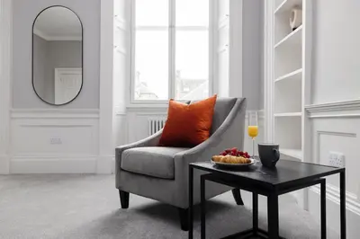 a living room with a chair and a table at JOIVY Luxurious Apt on Notable George Street in Edinburgh