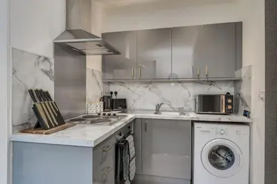 a white kitchen with a washing machine and a washer at The Garden Flat, Loch Lomond in Alexandria