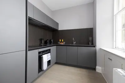 a kitchen with black and white cabinets and a window at JOIVY Modern Studio in New Town, on Historic George Street in Edinburgh