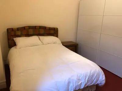 a bedroom with a white bed with a wooden headboard at Pier Head in Largs