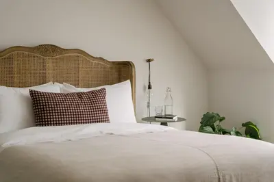a bedroom with a white bed with a wooden headboard at The Dundonald Guesthouse & Cottage in Culross