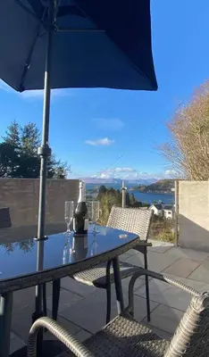 a table with an umbrella and two glasses on it at Seòmar Beag in Oban