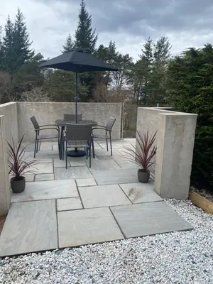 a patio with a table and chairs and an umbrella at Seòmar Beag in Oban