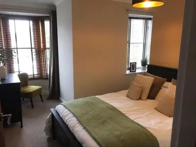 a bedroom with a bed and a desk and windows at Roselea Cottage in Luss