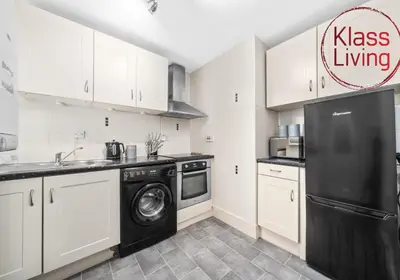 a kitchen with white cabinets and a black refrigerator at Garturk Apartment by Klass Living Coatbridge in Coatbridge