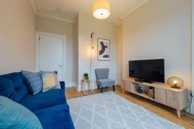 a living room with a blue couch and a television at The Trossachs Apartment in Doune