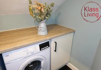 a vase of flowers on a counter next to a washing machine at Mossend Apartment by Klass Living Bellshill in Mossend