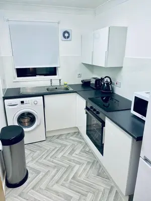 a white kitchen with a washing machine and a washer at Modern 2 Bedroom Apartment With Free Parking in Glasgow