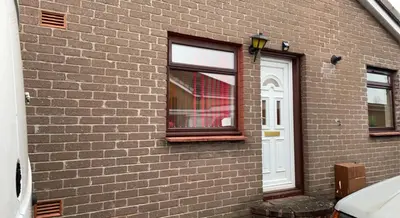 a brick building with a window and a white door at Wallace View - Holiday Home in Stirling