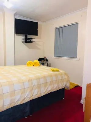 a bedroom with a bed with yellow towels on it at Wallace View - Holiday Home in Stirling