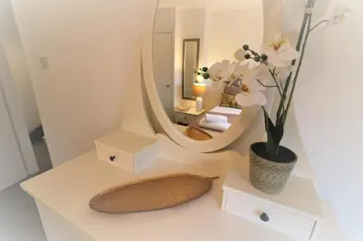a white table with a mirror and a vase of flowers at Signature - North View in Cambusnethan