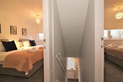 a bedroom with two beds and a stairway leading into a room at Signature - North View in Cambusnethan