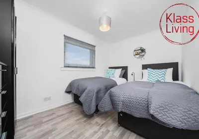two beds in a bedroom with white walls and wood floors at Berwick Apartment by Klass Living Coatbridge in Coatbridge