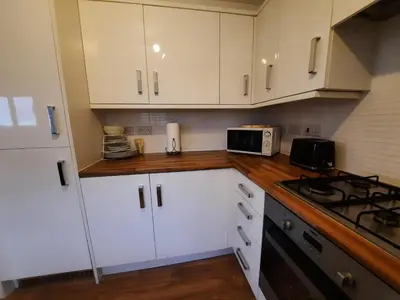 a kitchen with white cabinets and a stove top oven at Pond View Upper in Airdrie