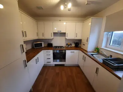 a kitchen with white cabinets and a sink at Pond View Upper in Airdrie
