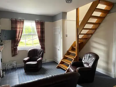 a living room with two chairs and a staircase at Rowan Cottage Wanlockhead Dumfries & Galloway in Wanlockhead