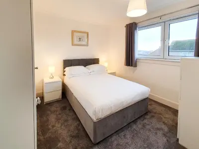 a bedroom with a bed and two windows at 3 bedroom house Amazon M90 Dunfermline Edinburgh in Fife