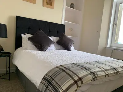 a bedroom with a large bed with a black headboard at clyde hub in Gourock