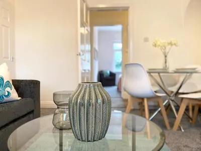 a living room with a glass table with a vase on it at Gladsmuir House in Glasgow