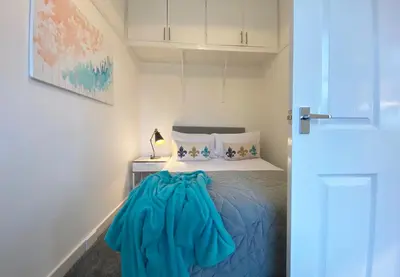 a bedroom with a bed with a blue blanket on it at Gladsmuir House in Glasgow
