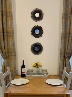 a table with a bottle of wine and two mirrors at Newly refurbished town centre apartment in Oban