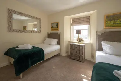 a bedroom with two beds and a mirror at Stormont House in Keilour