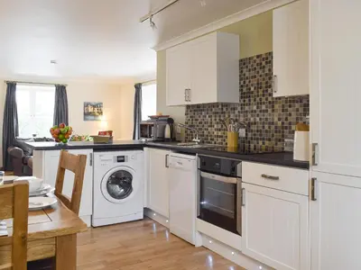 a kitchen with white cabinets and a washer and dryer at White Wisp in Kinross