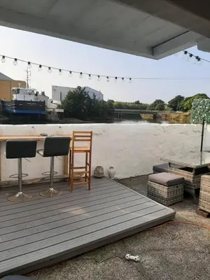 a wooden deck with a bar and two chairs and a table at Stunning Riverside Town House with views Ayrshire in Girvan