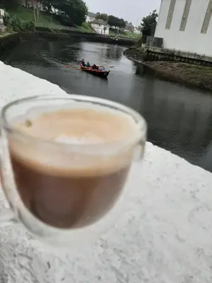 a cup of coffee sitting on a ledge next to a river at Stunning Riverside Town House with views Ayrshire in Girvan